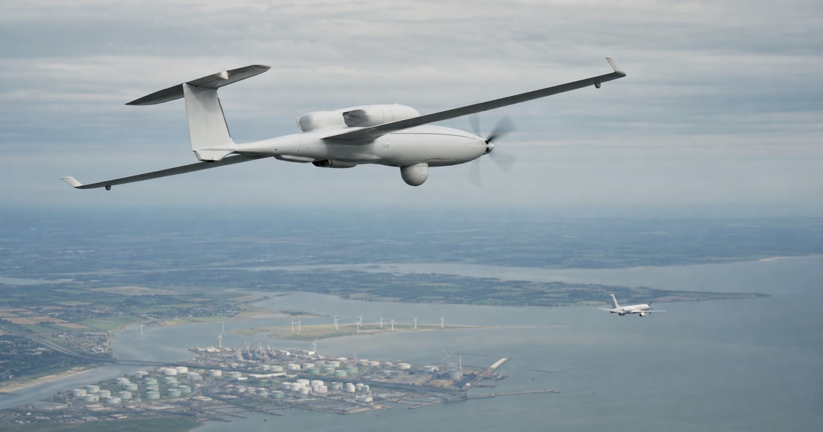 A long-endurance hydrogen UAV flying above a conventional passenger aircraft over an industrial coastline.